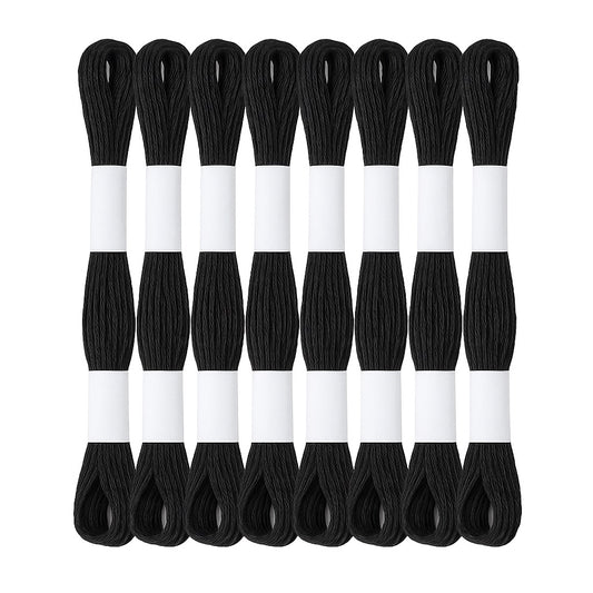 Madejas de hilo Mouliné en color negro dispuestas en semicírculo con etiquetas blancas sobre fondo blanco, ideales para bordado y proyectos artesanales.