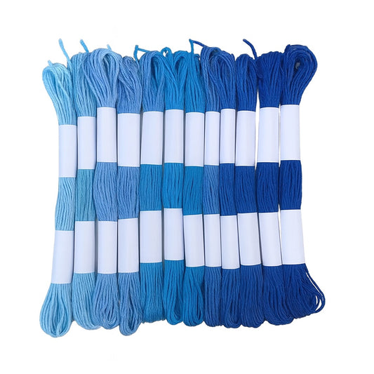 Madejas de hilo Mouliné en tonos azules, desde azul claro hasta azul marino, dispuestas en fila con etiquetas blancas sobre fondo blanco.