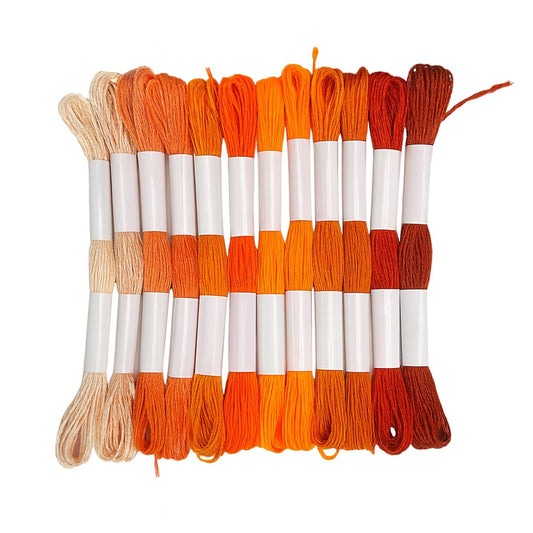 Madejas de hilo Mouliné en tonos naranjas, calabaza y terracota dispuestas en fila con etiquetas blancas sobre fondo blanco, ideales para bordado y manualidades creativas.