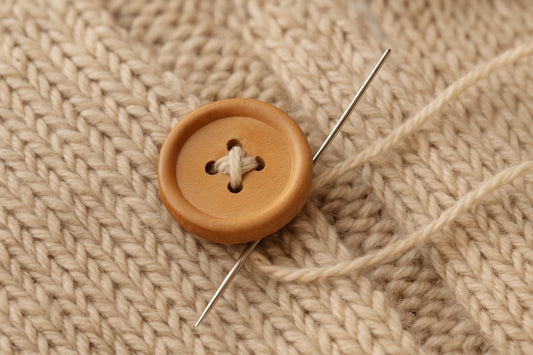 coser un botón en una prenda tejida a mano a punto o ganchillo