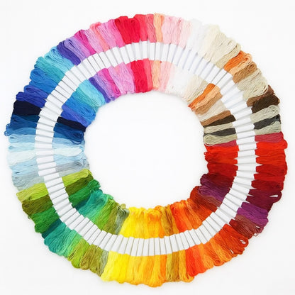 Madejas de hilo Mouliné en 100 colores diferentes dispuestas en círculo sobre fondo blanco, ideales para bordado y punto de cruz