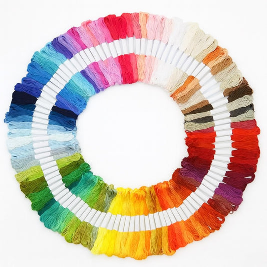 Madejas de hilo Mouliné en 100 colores diferentes dispuestas en círculo sobre fondo blanco, ideales para bordado y punto de cruz