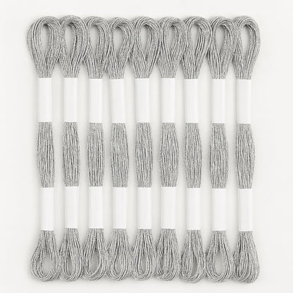 Madejas de hilo Mouliné metalizado color plata, pack de 12 unidades sobre fondo blanco, ideales para bordado decorativo y proyectos de punto de cruz